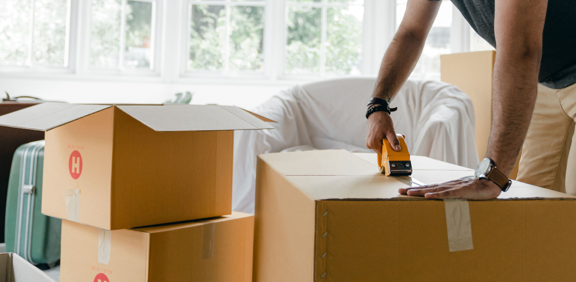 Mover sealing packed boxes in a bright home