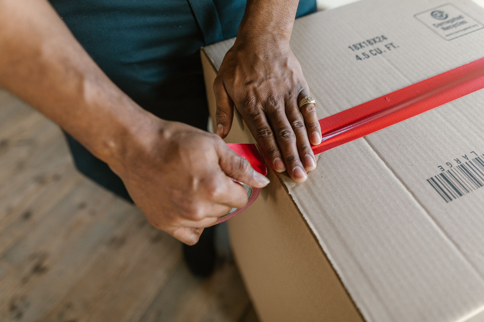 Mover securely sealing a moving box with packing tape